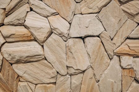 Detailed natural stone wall texture showcasing uneven rocks in beige tones.